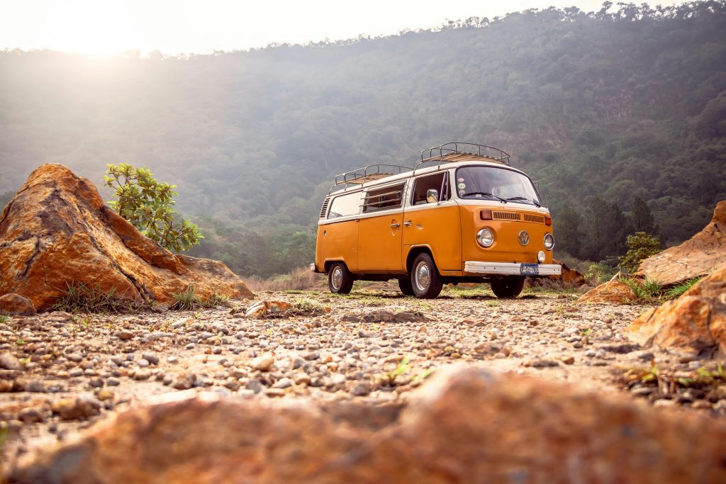 Classic VW van parked on rocky terrain with mountains in Alegría, El Salvador.
