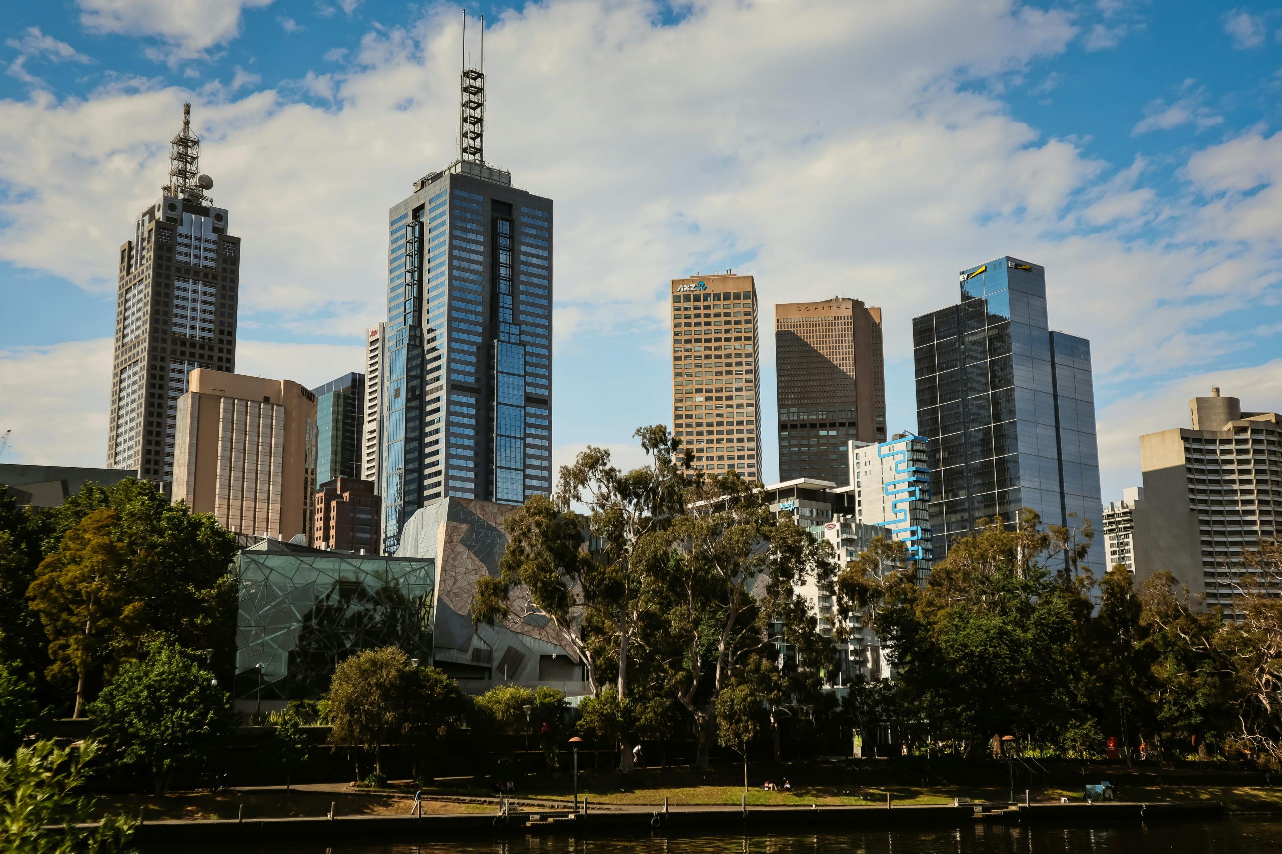 Stunning daytime view of Melbourne's modern skyline with high-rise buildings and lush greenery.